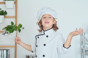 Little boy in chef uniform cooking at home