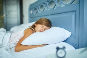 Little girl sleeping on a big and cozy bed white linen in the afternoon at home